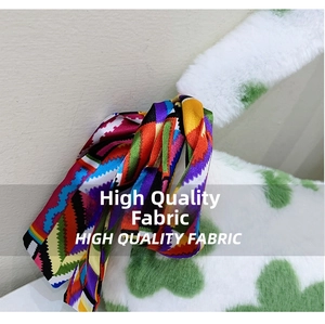 Detail shot of colorful geometric silk scarf tied on a green polka dot plush handbag