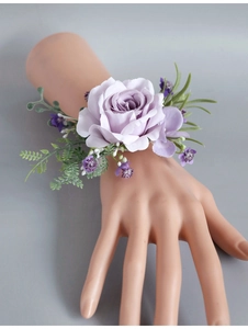 Detailed view of a purple silk rose wrist corsage with green leaves on a hand model