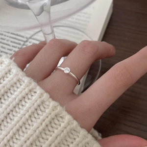 Close-up of elegant 925 sterling silver ring with zircon on hand with book background