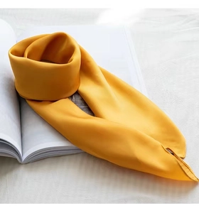 Detail of a soft yellow square silk scarf elegantly draped over an open book