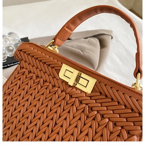 Close-up of brown woven faux leather handbag featuring a golden square twist lock