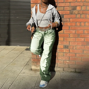 Detail of green tie-dye wide-leg trousers styled with a gray hoodie in a street setting