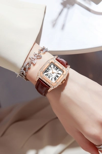 Detail of rose gold square watch with crystal bezel and brown leather strap on wrist