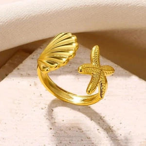 Close-up of golden starfish and seashell charms on an adjustable stainless steel ring
