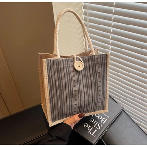 Close-up of linen tote bag with vertical stripes and large button closure detail