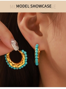 Model wearing bohemian gold drop earrings with sky blue beads and textured metal