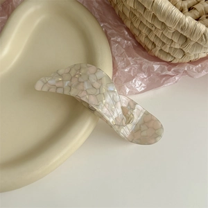 Macro shot of acetic acid hair clip with irregular patterns on a beige tray