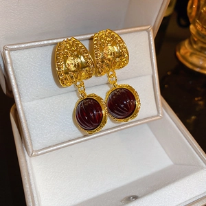 Detailed close-up of vintage gold earrings with deep red ribbed gemstone pendants