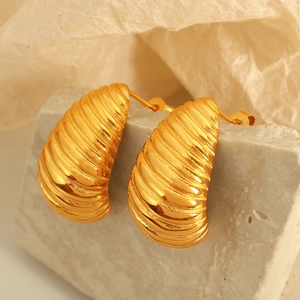Minimalist gold twist croissant earrings with metallic texture on stone stand