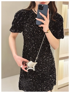 Close-up of a silver metallic star-shaped crossbody bag on a black sequin dress