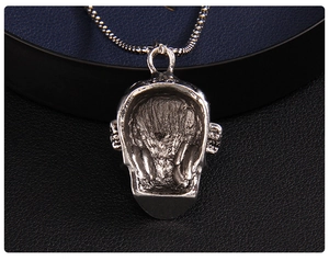 Gros plan détaillé du pendentif tête de mort punk argenté aux yeux en strass rouges