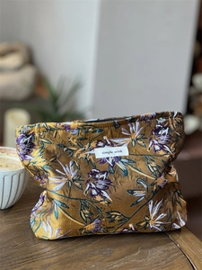 Detailed view of floral embroidery on a caramel toiletry bag with black zipper