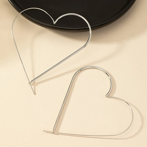 Minimalist silver oversized heart hook earrings with simple wire design on beige surface