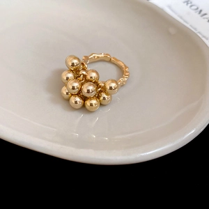 Detailed view of golden irregular ball ring with hammered texture on a ceramic tray