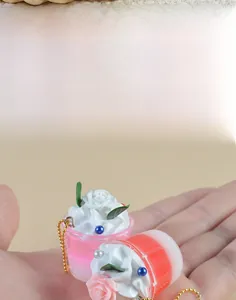 Detailed view of miniature ice cream cup keychain with pink cream and rose petal decor
