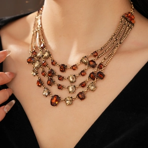 Detail of vintage layered necklace with amber oval crystals worn on a black V-neck top