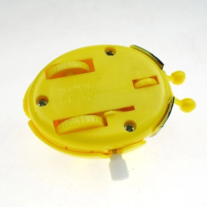 Bottom view of yellow clockwork beetle toy showing winding knob and plastic wheels