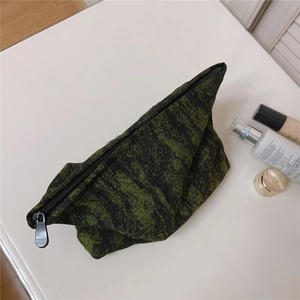 Macro view of green and black jacquard textured fabric cosmetic bag with top zipper