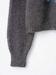 Detailed macro view of the fuzzy mohair knit texture and blue jacquard pattern on a gray sweater