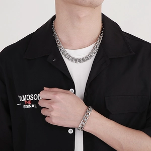 Close-up of a silver-tone thick curb chain necklace and bracelet set worn by a male model