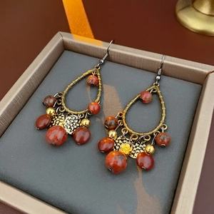 Close-up of bohemian water drop tassel earrings with bronze metal and red marble beads