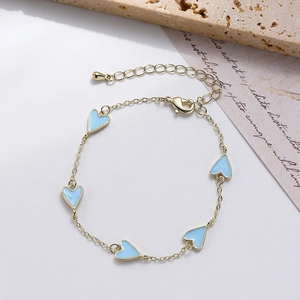 Macro detail of gold-tone bracelet featuring light blue enamel heart charms and clasp