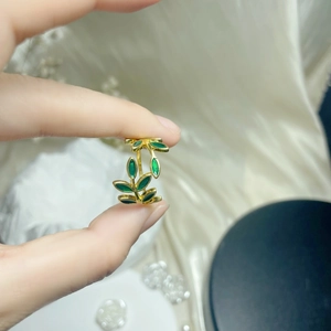 Macro detail of elegant golden copper leaf ring featuring green enamel inlay finish