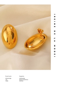 Close-up of polished 18K gold-plated oval stud earrings on soft silk fabric background