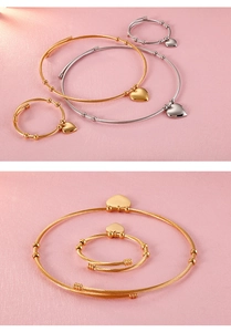 Detail view of gold and silver twisted wire jewelry set with heart charms on pink background