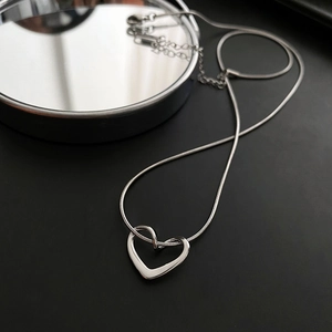 Macro shot of silver heart pendant necklace on dark surface with elegant reflection