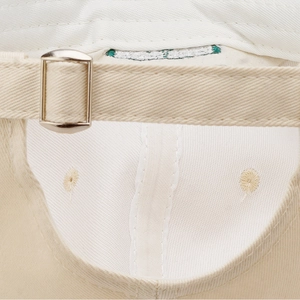 Adjustable back detail of a cream twill baseball cap with a silver metal slider buckle