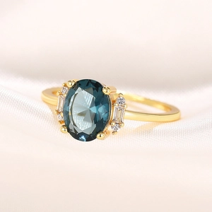 Macro shot of oval blue gemstone ring with accent diamonds on silk background