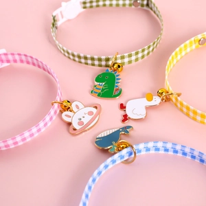 Detail of four plaid pet collars in pink green yellow blue with cute cartoon charms
