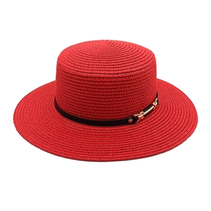 Vue détaillée d'un chapeau de paille rouge avec ruban noir et boucle en métal doré