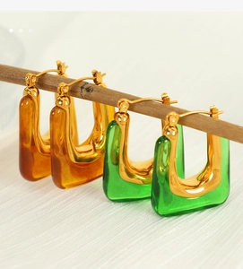 Detail view of amber and green resin U-shaped earrings on gold plating in high resolution