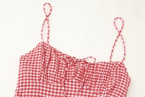 Detail of red gingham dress with adjustable spaghetti straps and front bow tie decoration