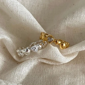 Detailed macro of gold and silver heart-shaped rings with sparkling zircon on fabric
