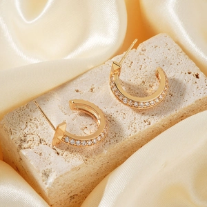 French style gold semi-circle copper earrings with micro-set zircons on beige travertine
