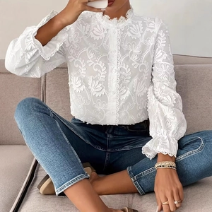 Détail d'une chemise blanche à manches longues avec broderie florale et dentelle fine