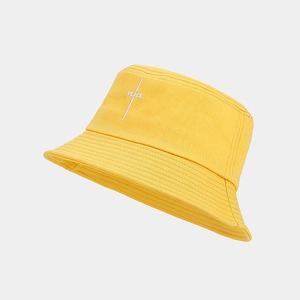 Detailed close-up of yellow cotton bucket hat with white Peace embroidery and fabric texture