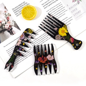 Artistic resin hair combs with embedded dried flowers and gold leaf on an open magazine
