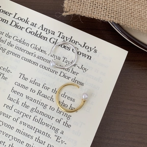 Detailed close-up of gold and silver minimalist open rings with white pearl accent