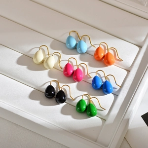 Macro shot of multi-color enamel water drop earrings in a white jewelry display tray
