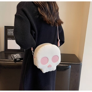 Detail of creative skull crossbody bag in cream and pink on a black knit dress