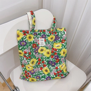 Dettaglio della borsa tote in cotone con stampa floreale e fragole su una sedia