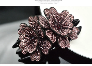 Gros plan sur une pince à cheveux fleurie en strass rose foncé avec base noire élégante