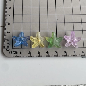 Macro detail of 2cm colorful gradient starfish beads with gold glitter on a measuring mat