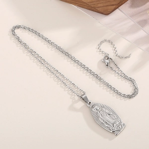 Dettaglio della collana con ciondolo Vergine Maria in argento su superficie beige con vassoio