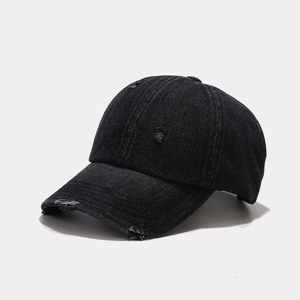 Detail showing distressed holes and vintage washed texture on black denim baseball cap