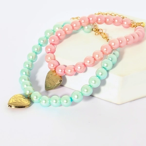 Close-up of pink and mint green pet pearl necklaces with golden heart love pendants